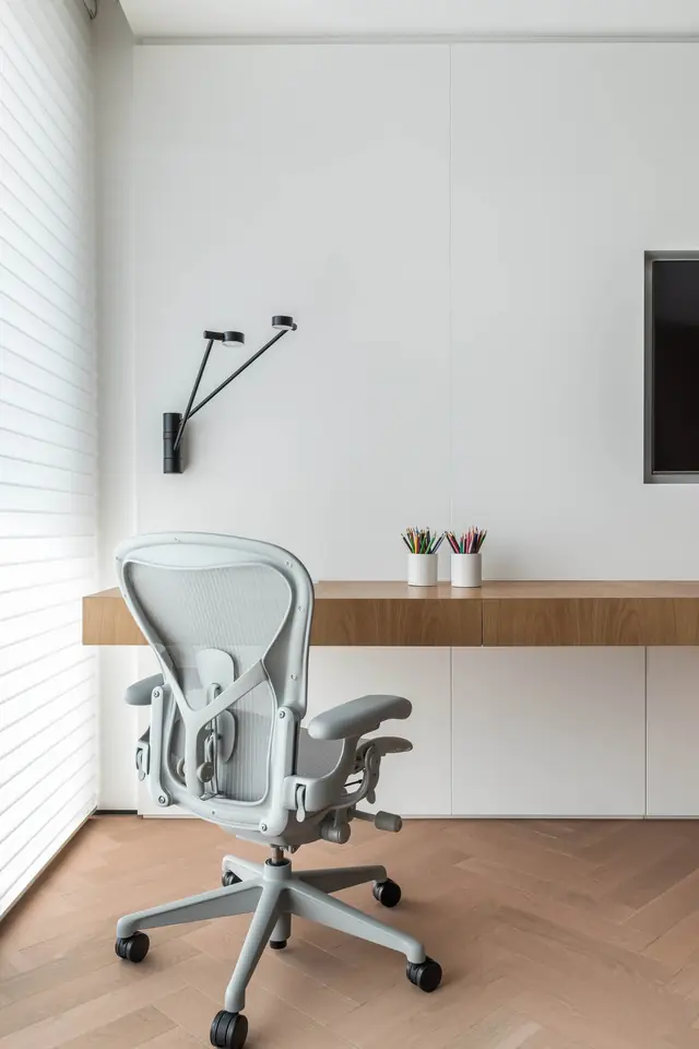 Home office com cadeira ergonômica e bancada em madeira